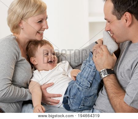 Happy family having fun together laughing, father kissing babies feet.