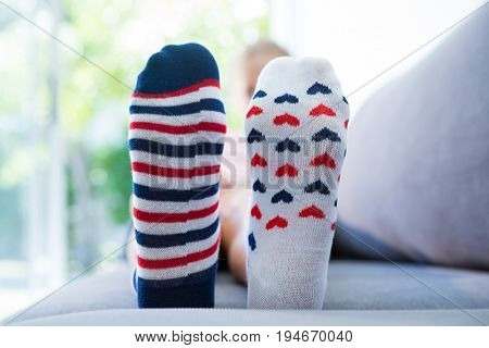 Close up of girl wearing different socks while sitting on sofa at home