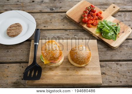High anlge view of burgers and vegetables on cutting board