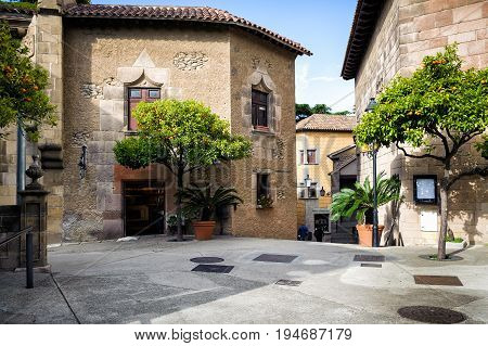 Traditional medieval square with citrus trees in Spanish village (Poble Espanyol) at Barcelona town, Catalonia, Spain