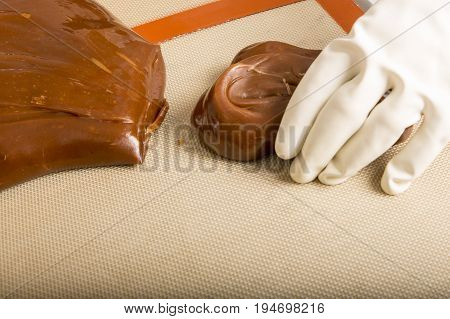 Artisanal production of caramel toffee sweets butterscotch candies. Woman with white lab coat blouse cutting rolls of sugar pastry to do butterscotch candies traditional sweetx of France