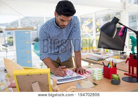 Male graphic designer working at desk in the office