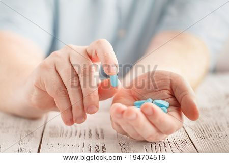 Male Hand Holding Blue Pills In Palm