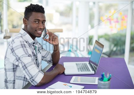 Portrait of smiling executive talking on mobile pone in office