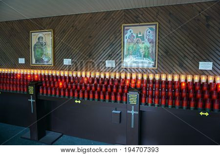 INDIAN RIVER, MICHIGAN / UNITED STATES - JUNE 18, 2017: Visitors and devotees may offer donations and light candles below religious pictures, at the Cross in the Woods Roman Catholic National Shrine.