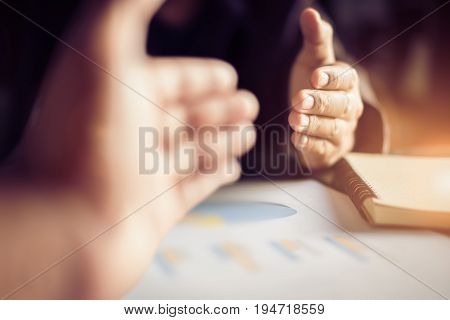 Business people handshake after meeting caption analyze graphs and goals set over blurred office.Film tones and Light fair