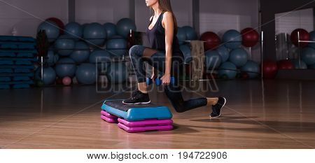 Fitness step, training, aerobics, sport concept - Athletic woman trainer at step doing aerobic with steppers indoors. Fitness woman with step platform doing workout