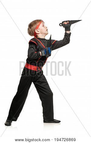 Young male fighter exercising with kunai throwing knives. Cosplay hero ninja