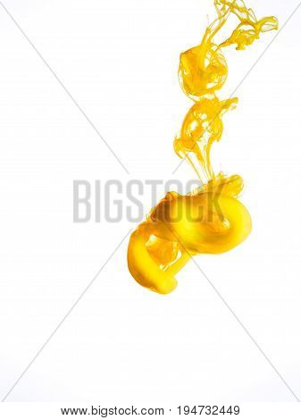 Ink swirl in water isolated on white background. The paint in the water. Soft dissemination a droplets of colored ink in water close-up. Abstract background. Explosion of splashes yellow acrylic ink.