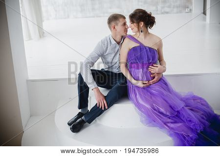 pregnant woman and man posing together in Studio, happy waiting