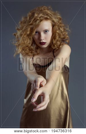 Inviting red-haired girl in a sexy golden dress