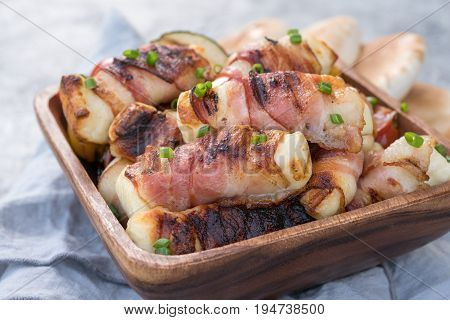 Grilled bacon wrapped haloumi cheese with vegetables and pita