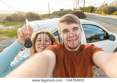 Young funny couple with keys to new car outdoor.