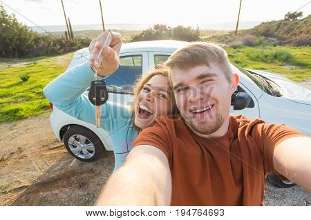 Young funny couple with keys to new car outdoor.