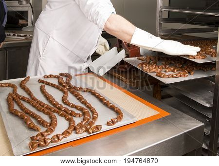 Artisanal production of caramel toffee sweets butterscotch candies. Woman with white lab coat blouse shaking separating removing the pieces of butterscotch candies traditional sweets of France