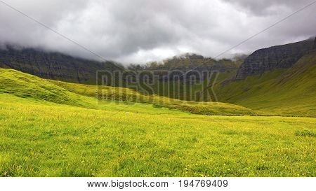 Green grass and mountains a cloudy day at Faroe Islands, Danmark. Rainy day in july.