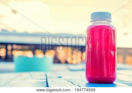 Close up soft fruit strawberry drink in plastic bottle on wooden table in outdoors restaurant