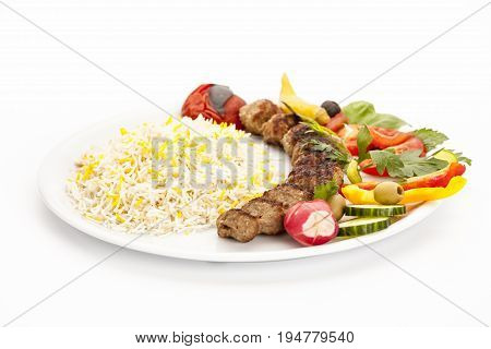 Crispy grilled lamb kebab taken off the skewer and served on a plain plate. Low angle view studio shot. Closeup. Barbecue meal fusion food concept Persian traditional dish or hearty eating.