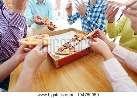 People hands grabbing pizza from delivery box closeup