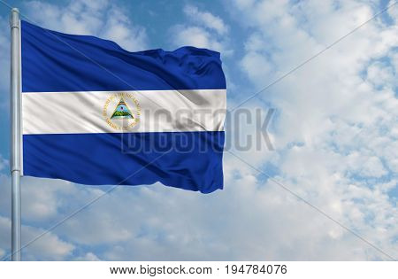 National flag of Nicaragua on a flagpole in front of blue sky.