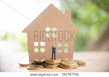 Miniature People,real Estate Investment. House And Coins On Table.