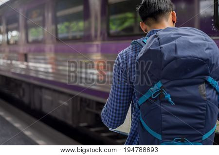man traveler with backpacker look searching location at trainstation travel concept