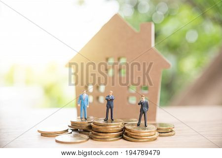 Miniature People,real Estate Investment. House And Coins On Table.