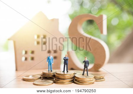 Miniature People,real Estate Investment. House And Coins On Table.