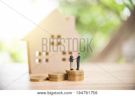 Miniature People,real Estate Investment. House And Coins On Table.