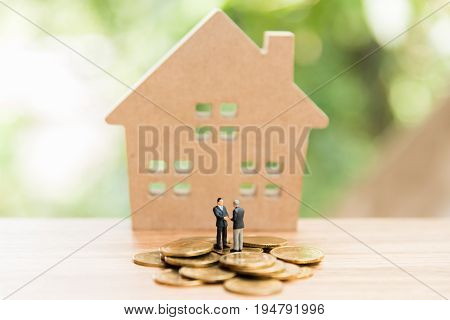 Miniature People,real Estate Investment. House And Coins On Table.