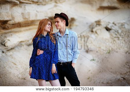 An Attractive Man Hugs A Beautiful Woman In A Blue Dress In The Middle Of A Sandy Canyon. Lovers Are