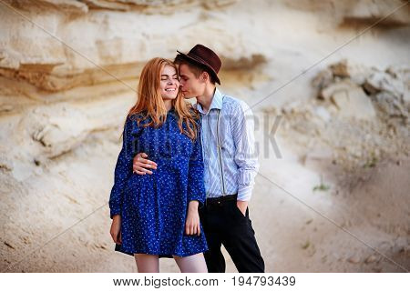 An Attractive Man Hugs A Beautiful Woman In A Blue Dress In The Middle Of A Sandy Canyon. Lovers Are