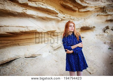 Beautiful Redheaded Girl Standing In A Blue Dress In The Middle Of A Sand Quarry