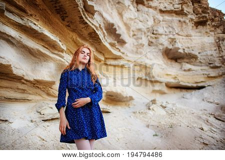 Beautiful Redheaded Girl Standing In A Blue Dress In The Middle Of A Sand Quarry