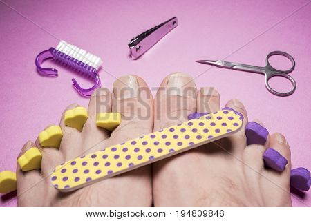 Male pedicure, nail file,  scissors on a pink background