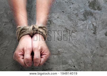 victim slave prosoner male hands tied by big rope in the concrete background. Concept image of people who addicted or slaved some bad thing.
