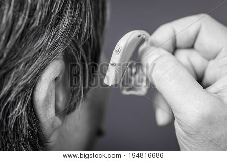 Closeup senior woman with hearing aid in her ear. Health care hear amplify device for the deaf.