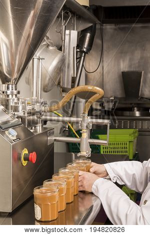 Automated food factory machine get the caramel jam in the jugs. Close up