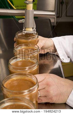 Automated food factory machine get the caramel jam in the jugs. Close up