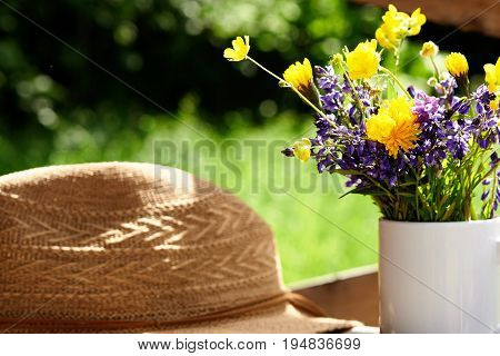 wild flowers and summer srtaw hat at sunny day