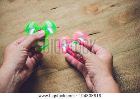 A Man Hand Holding Hand Spinner Or Fidget Spinner Over Wooden Background