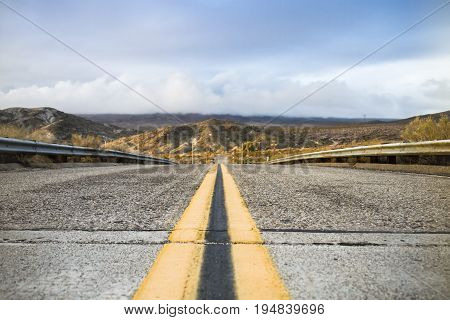 Road in California with mountains in the background and yellow road marking