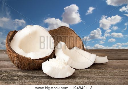 Halfs Of Coconut, Pieces Of Coconat, Coconut Flakes On  Blue Cloudy Sky Background.