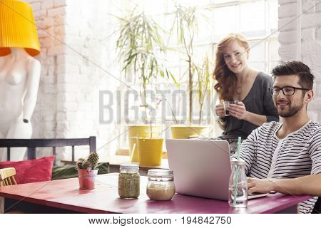 Young feelance graphic designers working in cafe with colorful furniture