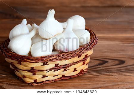 Raw whole garlic in a basket on a wooden background. Flavorful product, therapeutic food. Closeup