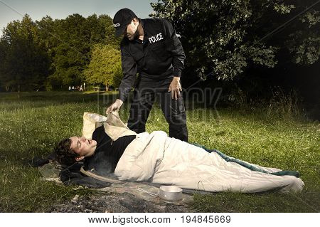 Vagabond young man sleeping in park checked by police patrol