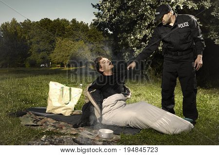 Vagabond young man sleeping in park checked by police patrol