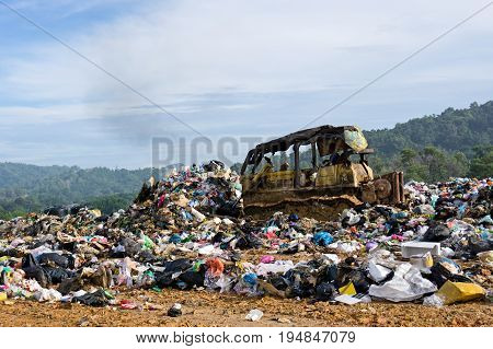 KOTA KINABALU MALAYSIA - 09 JULY 2017: Bulldozer truck flattening household garbage on a landfill waste site in Sabah.