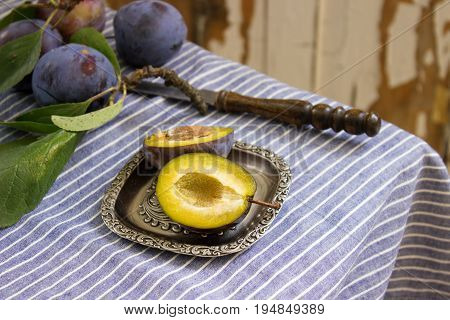 Ripe plums on a striped tablecloth and an old background