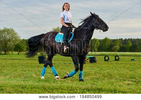 Pretty young girl riding a horse across country